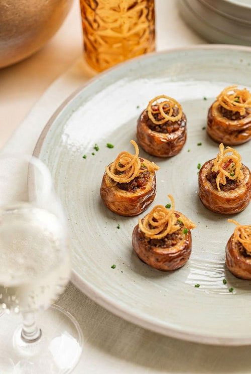Potatoes bites on ceramic platter topped with crispy shallots