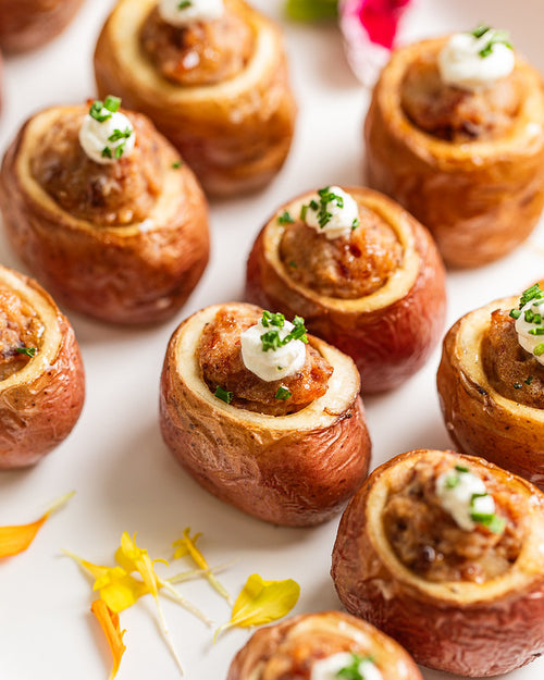 Platter of roasted new potatoes filled with bacon-manchego mixture, with a small dollop of sour cream and chives