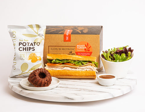 boxed lunch with classic turkey and cheese sandwich, bundt cake, potato chips, and side salad