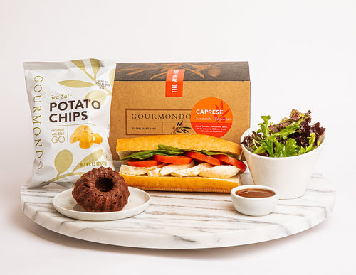 Boxed lunch with caprese sandwich, chips, side salad, and bundt cake 