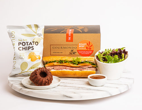 Boxed lunch with sandwich, bundt  cake, potato chips, and side salad

