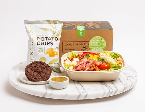 Box lunch of salad with italian meets, tomatoes, provolone and chickpeas, with cookie and chips as a side