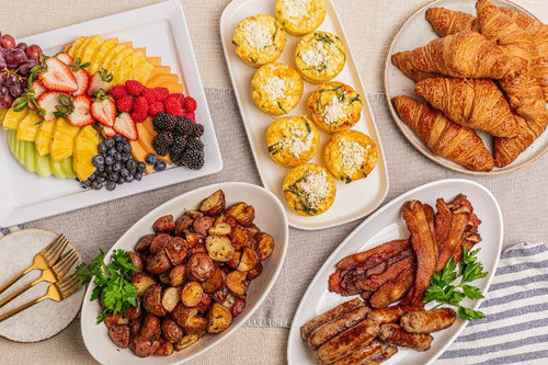 Package meal of classic breakfast offerings including egg frittatas, potatoes, fruit, croissants, bacon and sausge