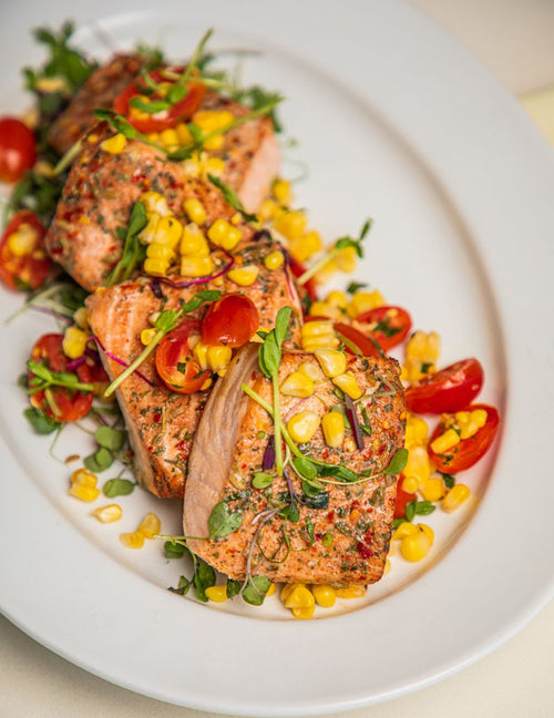Platter of salmon filets in a mesquite marinated, topped with corn and tomatoes