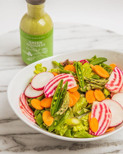 Serving bowl with mixed greens, julienned vegetables, and green goddess dressing
