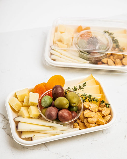 Individual tray with assorted cheeses, dried fruit, olives, and almonds