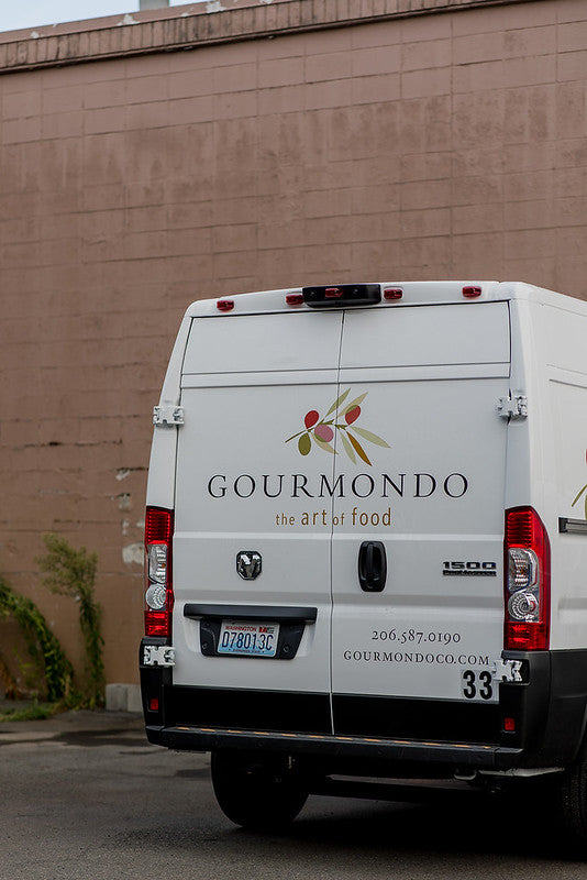 Gourmondo delivery van parked in front of brick building
