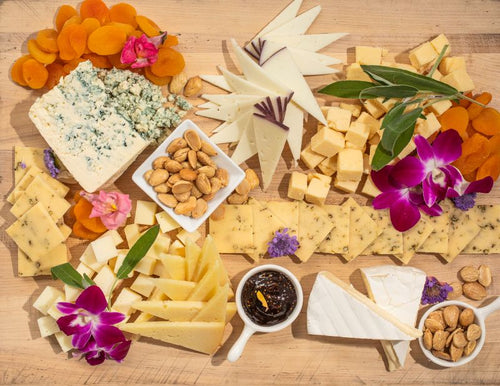 Wooden board with assorted cheeses, dried fruit, and almonds
