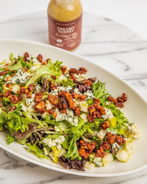 Serving bowl of mixed greens salad with candied walnuts, pears, and bleu cheese