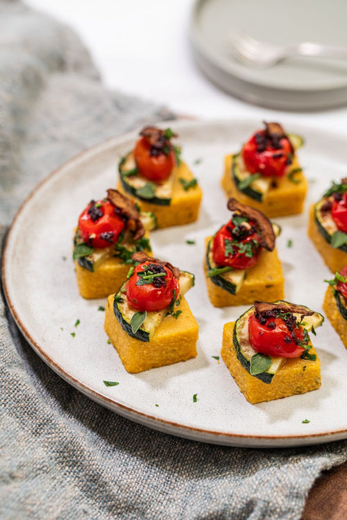 Mini polenta bites topped with zucchini, blistered tomato, and olives