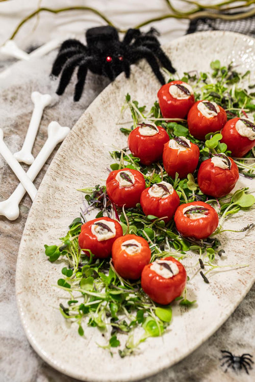 Peppadew peppers with goat cheese filling, plated with halloween decorations of spiders and bones