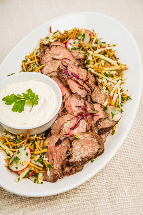Platter of sliced beef loin with carrot and radish garnish, served with horseradish sauce