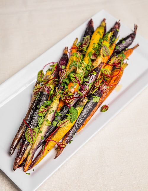 Platter of roasted rainbow carrots topped with fresh herbs