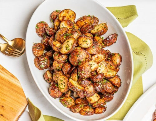 Herb roasted potatoes on a white platter, with green linen underneath