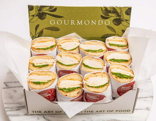 Box of sandwich halves of chicken, swiss, tomato aioli, and lettuce on baguette