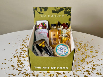 Kit of mini blowers, bottled immunity tonic, mini foil wrapped chocolate cake, in a Gourmondo branded box 