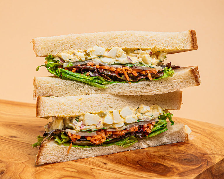 Halves of egg salad sandwich stacked on top off each other, with Vietnamese veggies