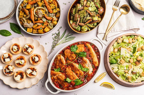 Gourmet Italian catering featuring chicken puttanesca, fresh Caesar salad, roasted vegetables, herb potato salad, and elegant individual desserts, perfect for corporate lunches, meetings, and special events.
