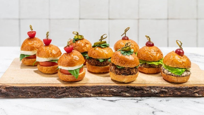 Assorted sliders on a wooden blank on top of marble counter