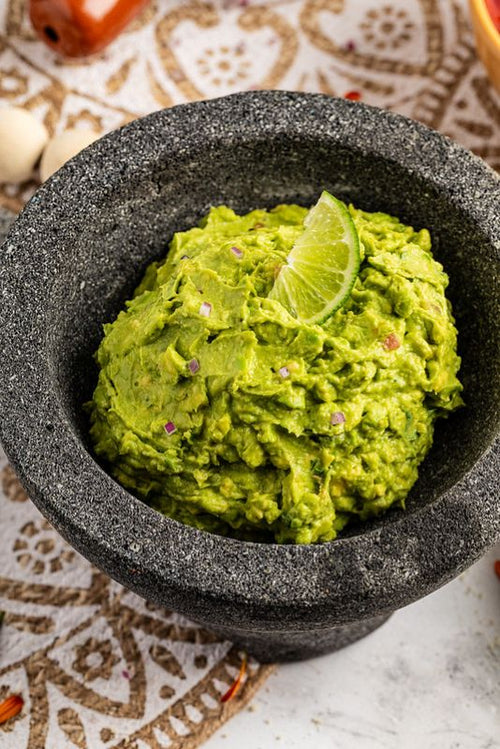 Fresh guacamole in a mortar topped with lime wedge