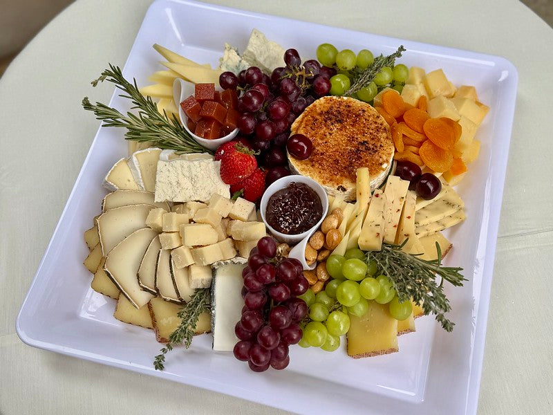 Assortment of cheeses, marcona almonds, and grapes with fig jam, and a side of crackers and breads