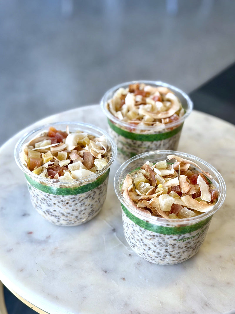 overnight oats with tropical dried fruits, toasted coconut, and soy milk in a clear compostable container