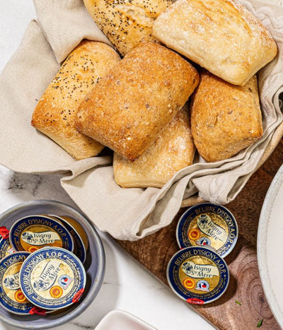 Basket of bread rolls with individual cups of butter