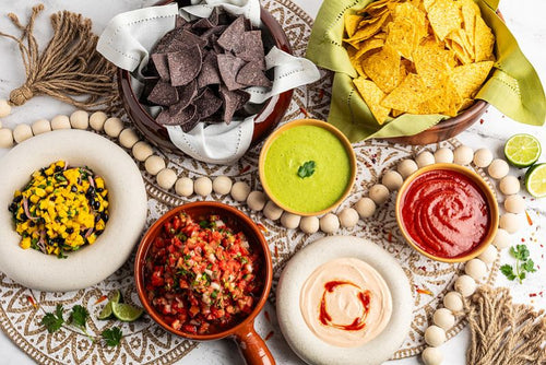 Assorted salsas including pico, mango salsa, and salsa verde, with blue and yellow corn chips 