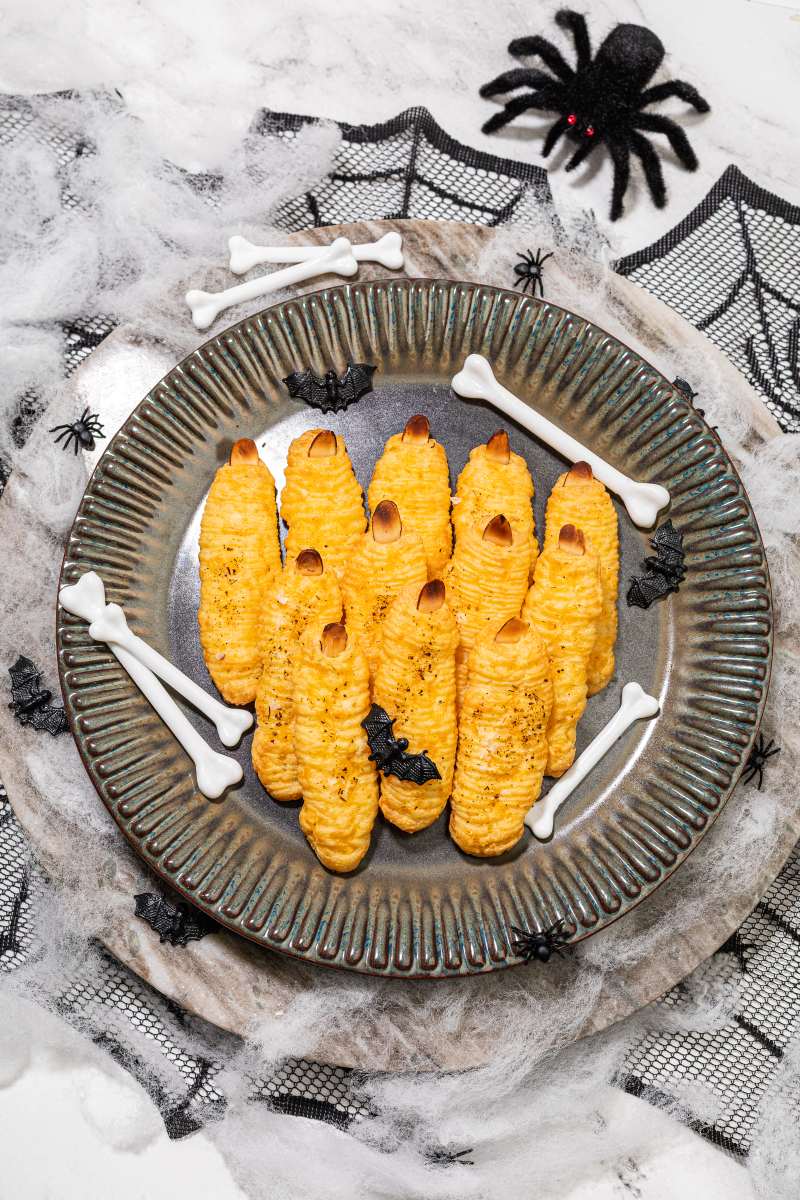 cheddar pastry baked with an almond nail to resemble a finger, plated with halloween decorations of bones and bats